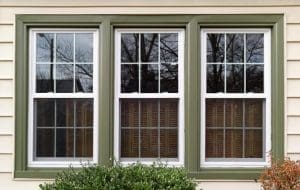 Three new replacement windows with green trim on front of house. Horizontal